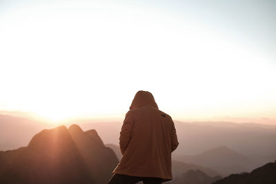 Rear view of woman standing against clear sky during sunset