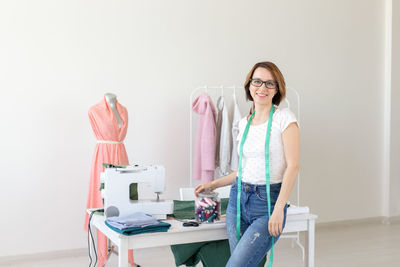 Portrait of smiling young woman standing against table