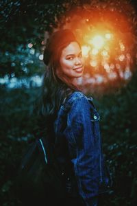 Portrait of woman standing against tree