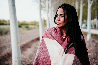 Smiling woman looking away while standing amidst trees