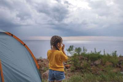 Family local getaway. kid sitting in the camping tent at campsite and looking at sunset