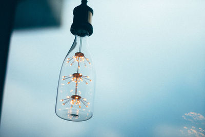 Low angle view of light bulbs hanging against wall