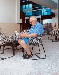 Senior man reading newspaper while sitting on chair