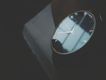 Close-up of clock with book on black background