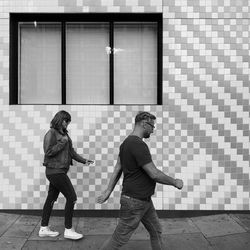 Full length of man and woman walking on floor in city