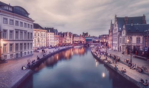 Canal amidst buildings in city against sky at dusk