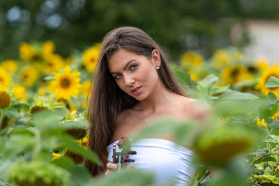 Portrait of young woman with pink flower in garden