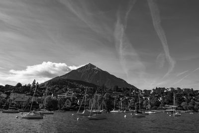 Boats moored in harbor against mountain
