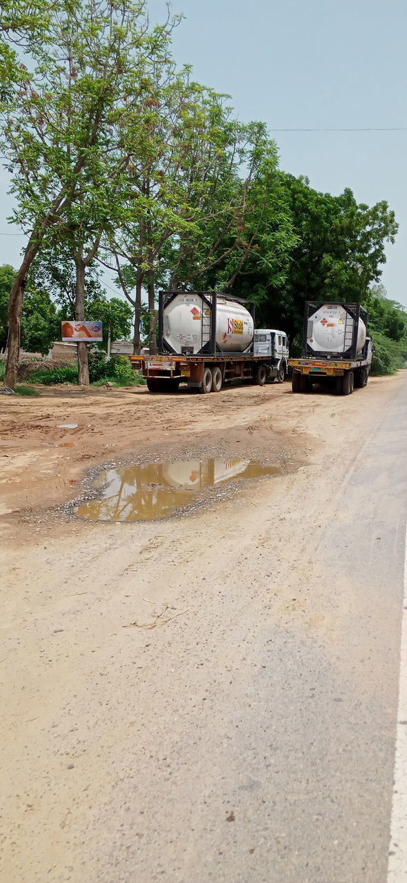 VEHICLES ON ROAD AGAINST TREES