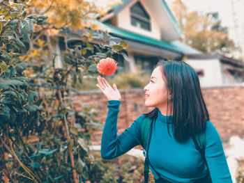 Close-up of young woman standing by orange flower blooming on plant