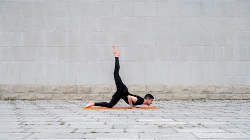 Full length of man exercising against wall