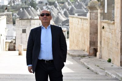 Portrait of mature man wearing sunglasses while standing on city street