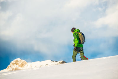 Man with umbrella on snowcapped mountain against sky