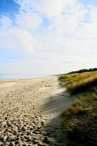 View of calm beach against cloudy sky