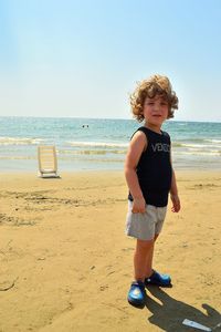 Full length of boy standing on beach against sky