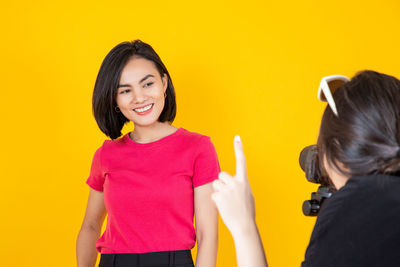 Portrait of a smiling young woman against yellow background