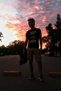 Full length of man looking at camera against sky during sunset