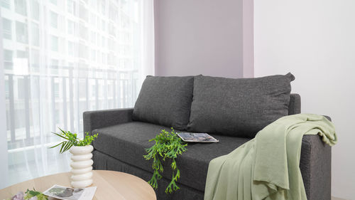 Low section of woman sitting on sofa at home