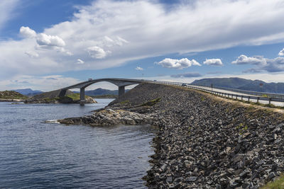 Bridge over river against cloudy sky