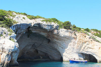 Rock formations by sea against clear blue sky