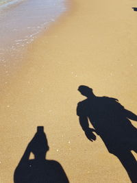 Shadow of people on sand at beach