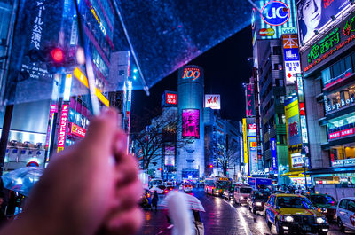 Midsection of man photographing illuminated city against sky at night