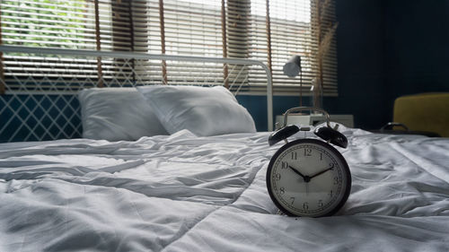 Close-up of alarm clock on bed at home