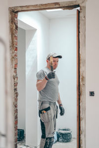 A man working with a crowbar in a doorway.