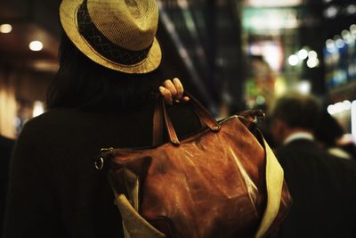 Rear view of woman wearing hat holding bag
