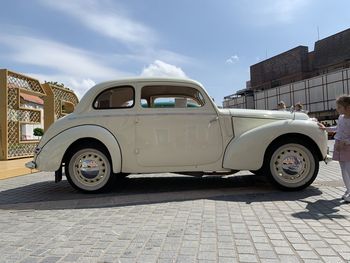 Vintage car on street in city against sky