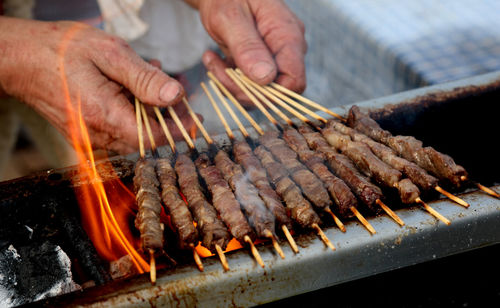 Close-up of person preparing food on barbecue grill