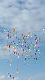 Low angle view of colorful balloons flying against sky