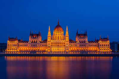 Illuminated parliament building against blue sky at night