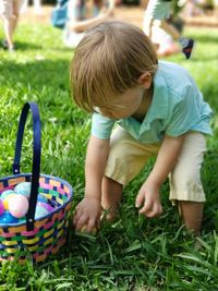 Boy holding easter egg while standing on grass