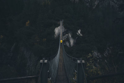 Rear view of man walking on rope bridge