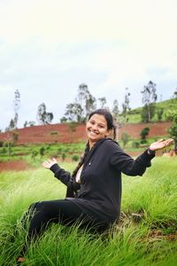 Portrait of a smiling young woman sitting on field