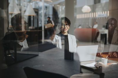 Smiling businesswoman discussing ideas with businessmen during meeting in office