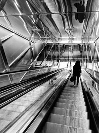 Rear view of man walking on escalator