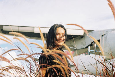 Portrait of smiling young woman standing against sky