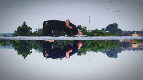 Man with woman sitting by lake against sky