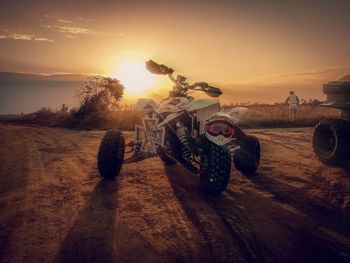 Quadbike on sand against sky during sunset