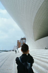 Rear view of woman standing on road in city