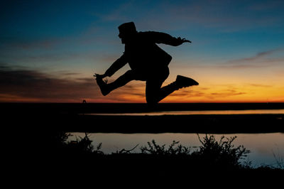 Silhouette man jumping against sky during sunset