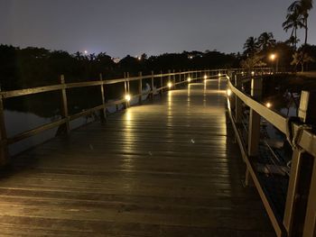 Footbridge over illuminated bridge against sky at night