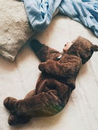 High angle view of baby in bear costume sleeping on bed
