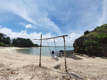 Rear view of woman sitting on swing against sea