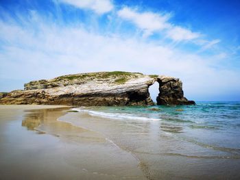 Rock formation on beach against sky