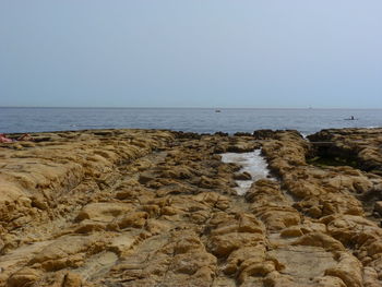 Scenic view of rocks on beach against clear sky