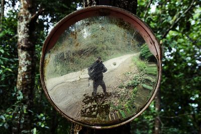 Reflection of man on mirror in forest