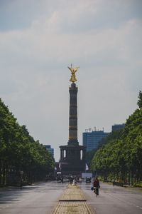 Statue in city against cloudy sky